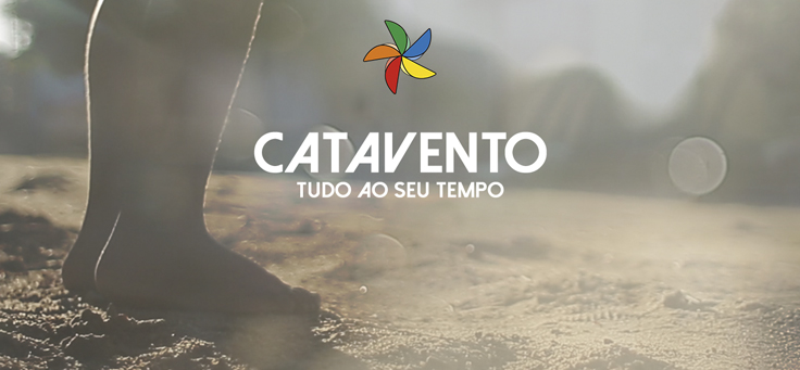 Imagem mostra o logo do comentário cata-vento. Ao fundo aparece os pés de uma criança