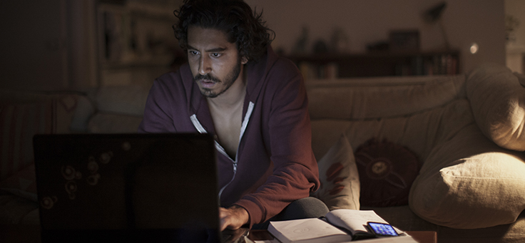 Imagem mostra o ator Dev Patel olhando para um computador em cena do filme Lion