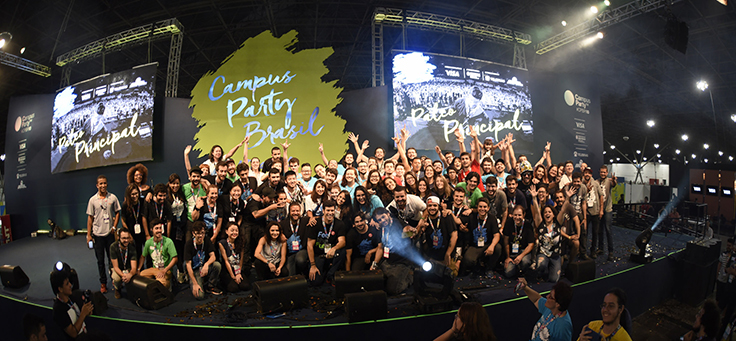 Imagem mostra muitas pessoas reunidas em um palco. Ao fundo se lê Campus Party