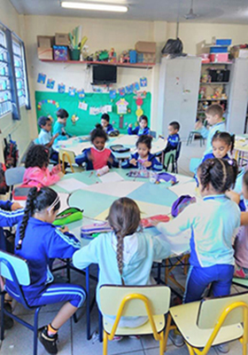 Imagem mostra crianças sentadas em roda na sala de aula