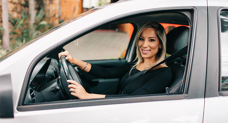 Mulher de cabelo loiro ao volante de carro tira foto de perfil