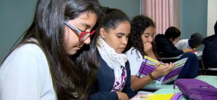 Em sala de aula, três estudantes participam de atividade do Programa Semente, acompanhando o conteúdo pelos livros