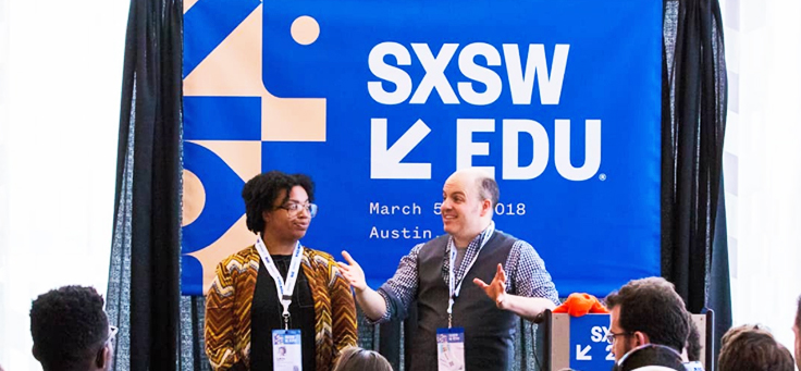 Imagem mostra duas pessoas à frente de um painel onde se lê SXSW Edu