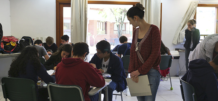 Imagem mostra professora em sala de aulas com alunos sentados em grupos