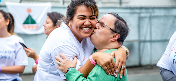 Colaborador abraça jovem em instituição durante o dia dos voluntários