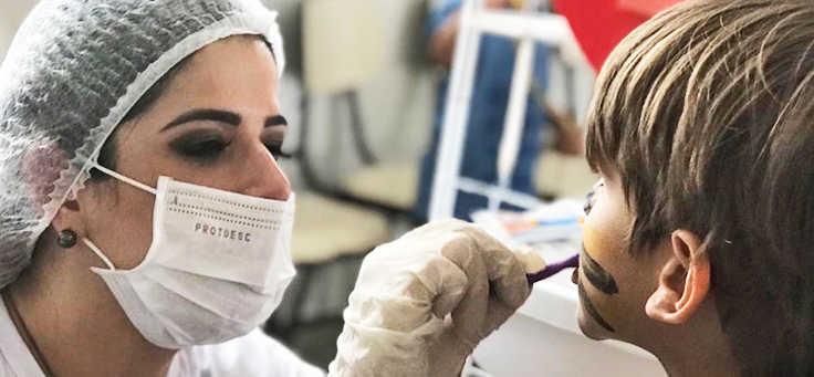 Voluntária verifica dente de criança durante dia dos voluntários