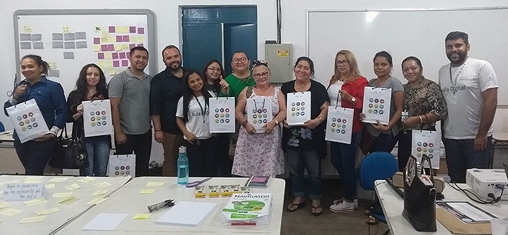 Cerca de 12 professores estão enfileirados exibindo trabalho de oficina realizada no evento Socialização de Práticas Formativas, em Manaus, que discutiu boas práticas pedagógicas.