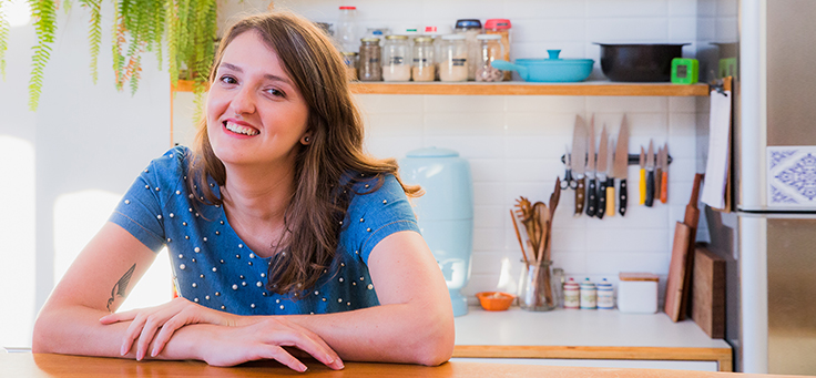 Cristal Muniz, autora do blog Um ano sem lixo, está com os braços cruzados sobre uma mesa e sorrindo para foto – matéria sobre como viver sem gerar lixo foi destaque em Voluntariado em 2018.