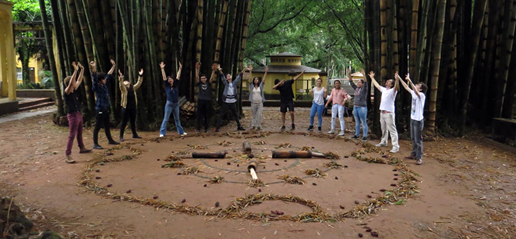 Na imagem, alunos realizam uma performance em um jardim, inspirados por artistas plásticos brasileiros.