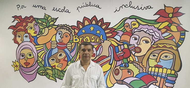 Diretor da Escola Infante Dom Henrique, que recebe refugiados, posa para foto com um painel ao fundo