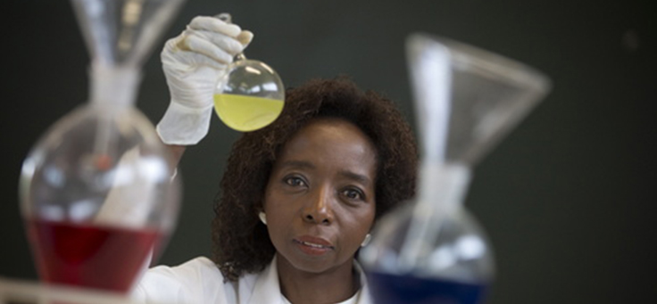 A imagem mostra a cientista Joana D’arc entre tubos de ensaio de um laboratório