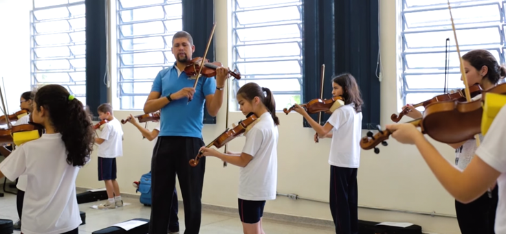 O professor de violino Ezequiel Sieba está em sala de aula com os alunos tocando violino