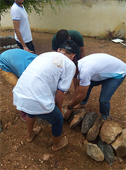 Imagem mostra estudantes arrumando cordão de pedras