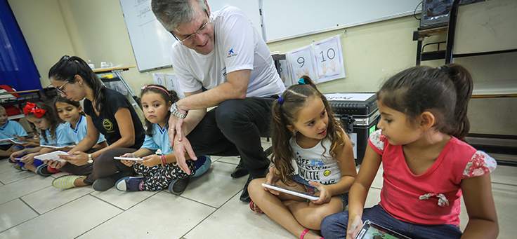 Crianças sentadas em roda interagem entre si e com educadores durante entrega de kits tecnológicos do Aula Digital, que incentiva a inclusão digital, em Viamão (RS).