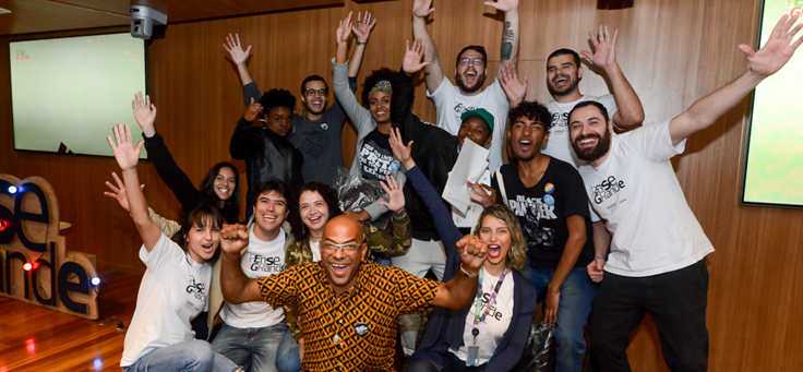 Participantes do Projeto Voluntários Pense Grande posam para foto em grupo em cima de um palco