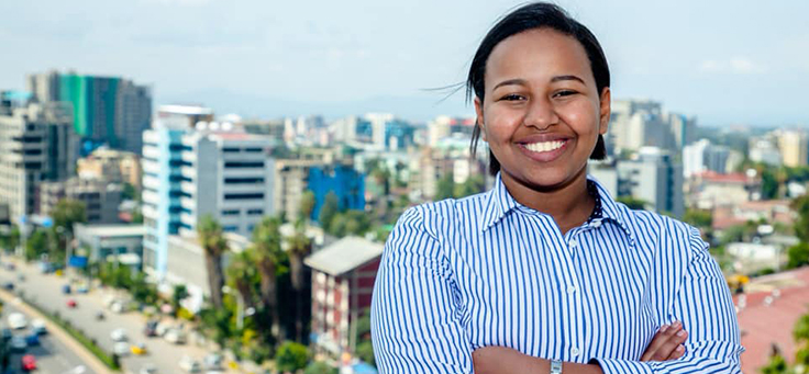 Imagem mostra a jovem Betelhem Dessie de camisa azul e branca. Ao fundo se vê a cidade de Addis Abeba, na Etiópia