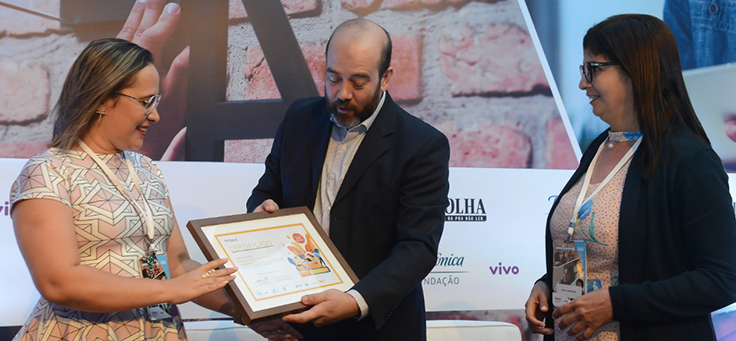 Imagem mostra participantes do grupo Santa Terezinha recebendo prêmio de Americo Mattar, Diretor-Presidente da Fundação Telefônica Vivo