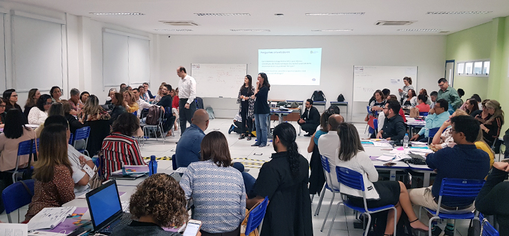 Imagem mostra técnicos de secretarias de ensino de diversos Estados reunidos em grupos em uma sala de aula durante evento do Consed para discussão do novo ensino médio.