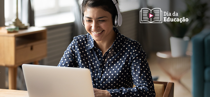 Mulher sorri e olha para tela de notebook enquanto usa fones de ouvido para ilustrar exemplos de boas práticas na educação a distância.