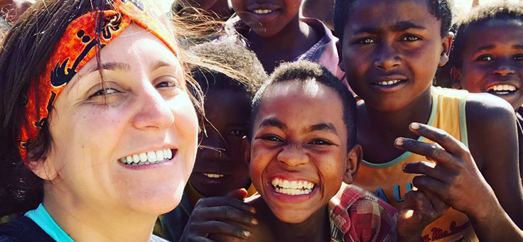 Imagem mostra Iara Xavier, do Caçadores de Bons Exemplos, abraçada com crianças. Todos sorriem para a câmera.