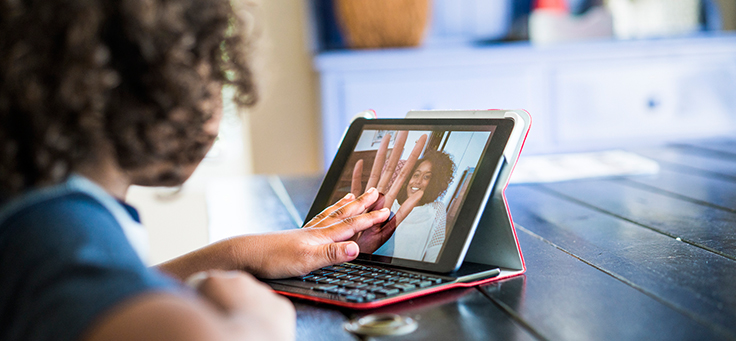 Imagem mostra uma menina colocando a mão na tela de um tablet