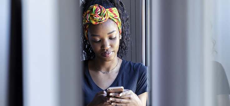 Imagem mostra uma jovem olhando para o celular