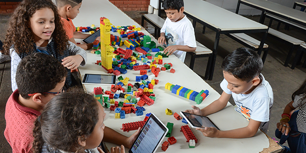 Crianças brincam com peças de lego e manuseiam o tablet do projeto Aula Digital ProFuturo em Goiânia