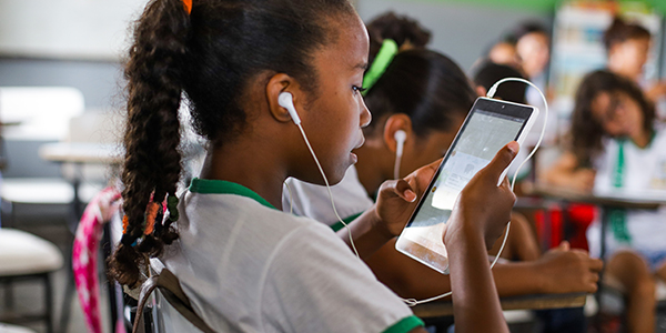 Criança em sala de aula está com fones de ouvido enquanto manueia o tablet do projeto Aula Digital ProFuturo em Sergipe