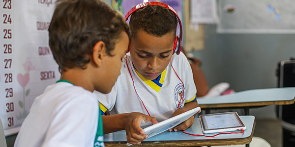 Criança em sala de aula está com fones de ouvido enquanto manueia o tablet do projeto Aula Digital ProFuturo em Sergipe