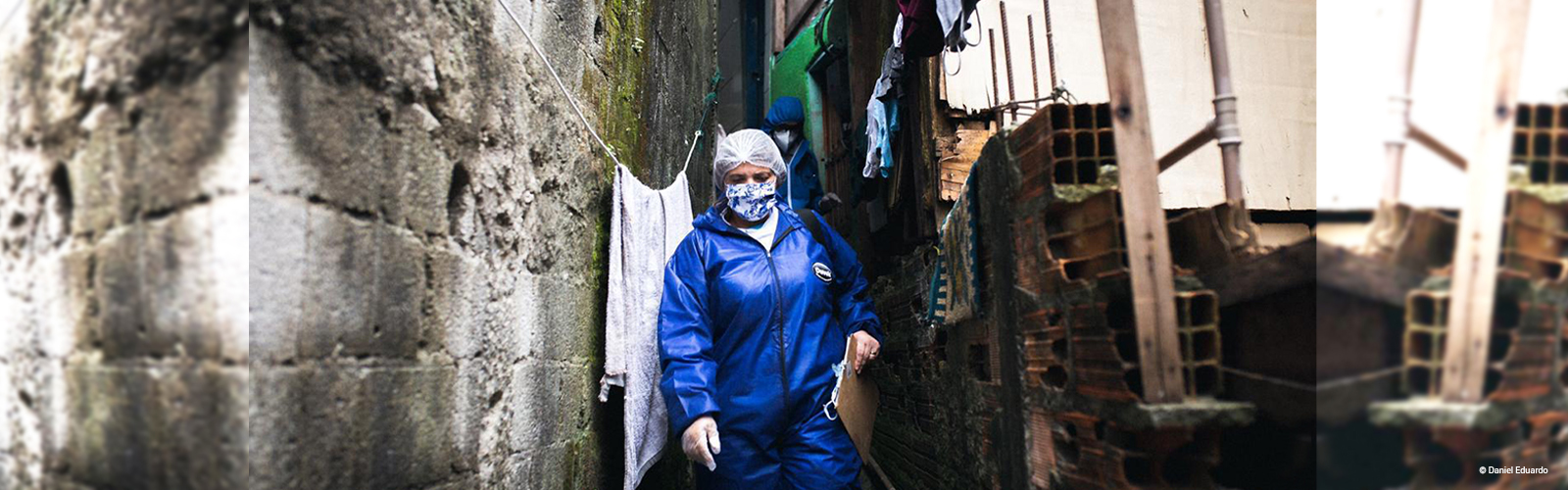 Imagem mostra uma mulher de máscara de proteção e agasalho azul andando pela comunidade de Paraisópolis