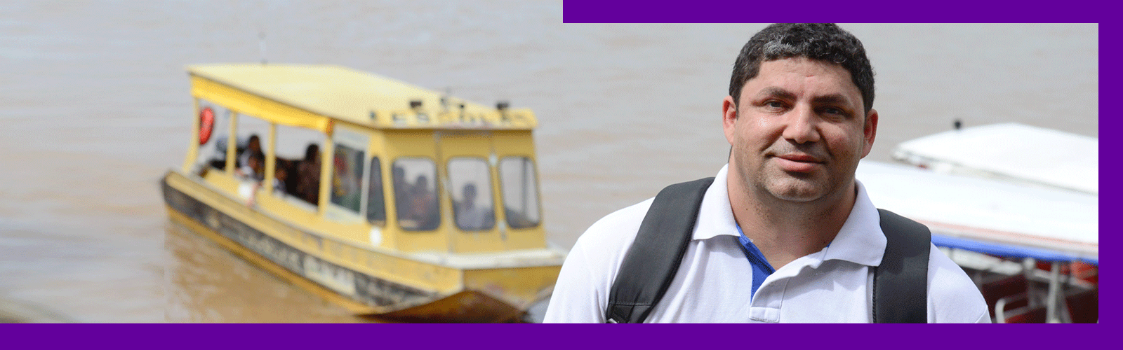 O Prof. Gilson da Silva, que atuou em escola atendida dentro do projeto Aula Digital, está sorrindo e, ao fundo, barcos se movimentam por rio que corta a cidade de Manaus (AM).