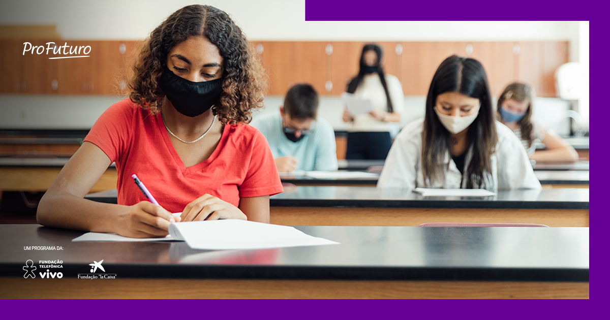 Imagem de estudantes fazendo prova em sala, com máscaras e distanciamento social