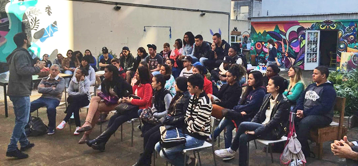 Jovens sentados em cadeira formam plateia em palestra de projeto ligado ao Visionários da Cidade, que criou metodologia empreendedora para jovens da periferia