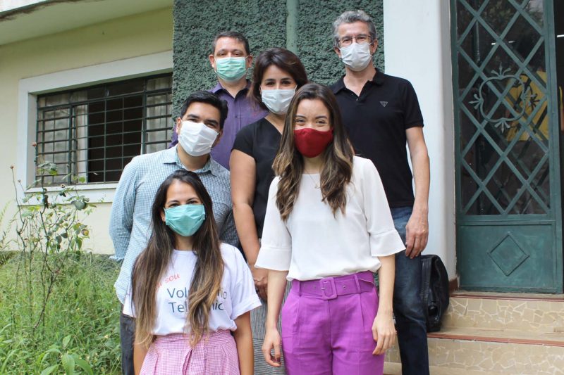 Imagem mostra três homens e três mulheres. Todos usam máscaras e estão em frente à sede da AFESU