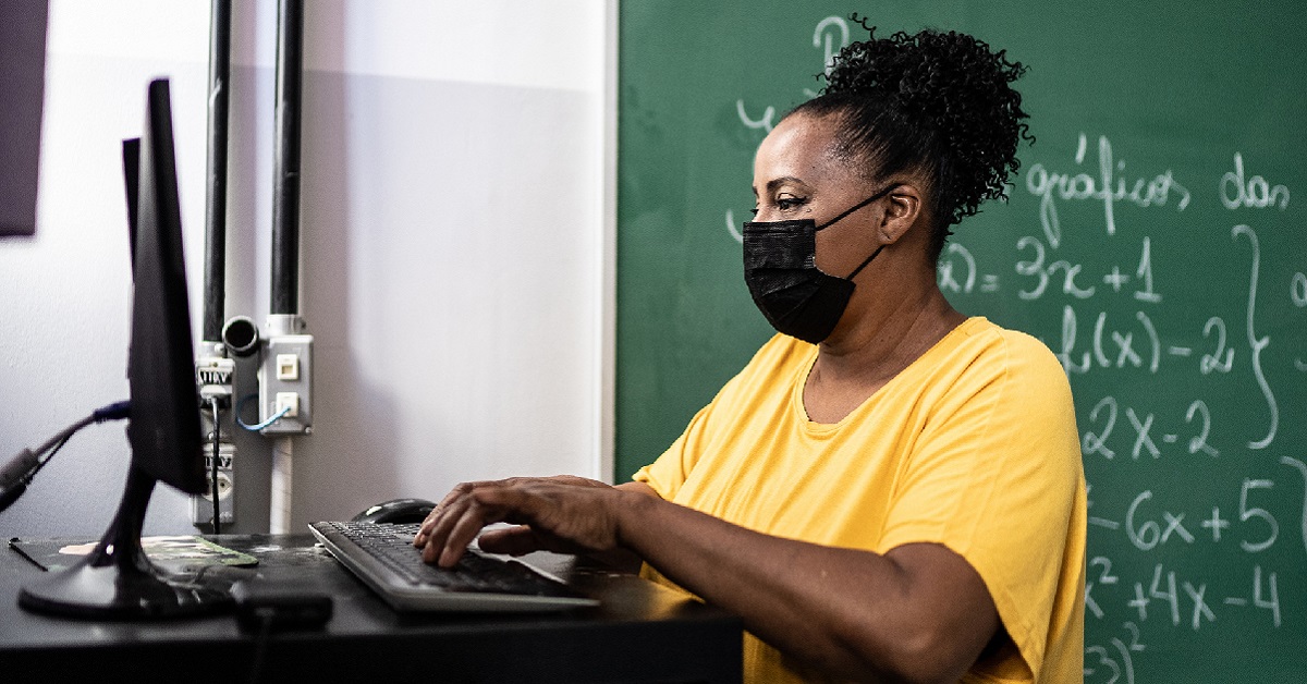 Foto de professora sentada, usando um computador, reforçando o posicionamento da Fundação Telefônica Vivo de Educar para Digitalizar