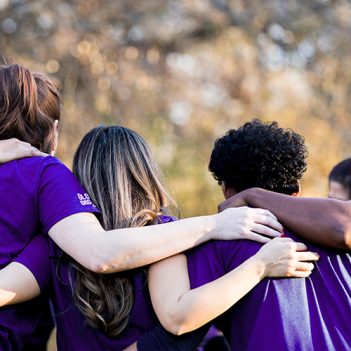 grupo de pessoas que fazem voluntariado no Brasil se abraçam em uma roda