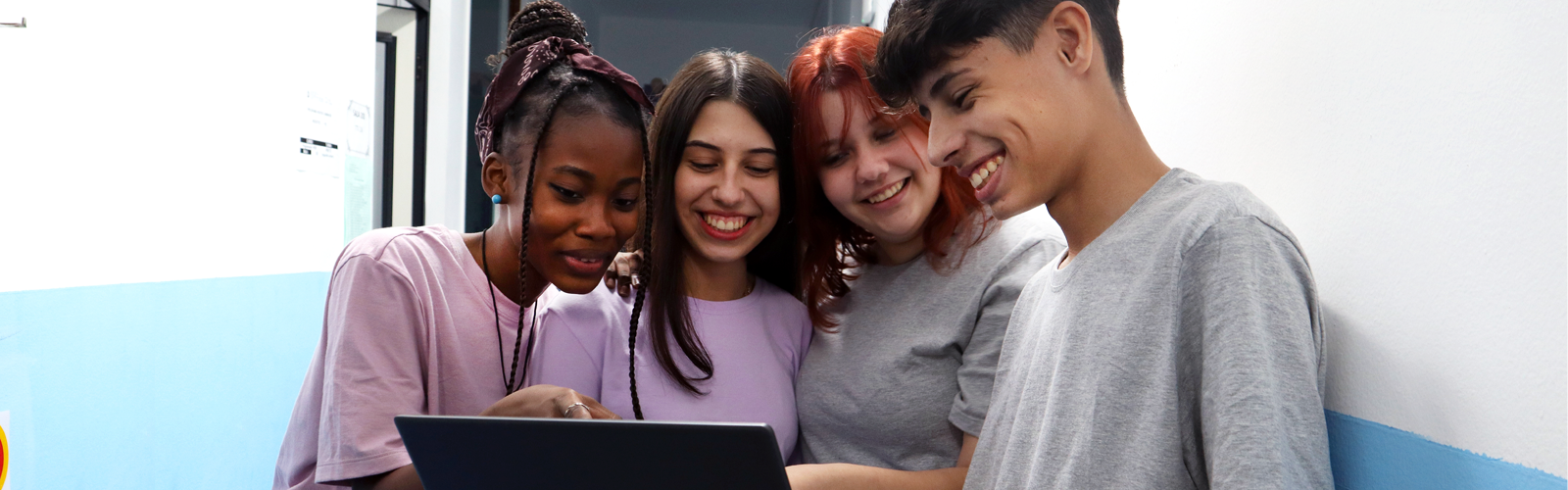 Grupo de quatro jovens na escola diante de um notebook (Pense Grande Tech)