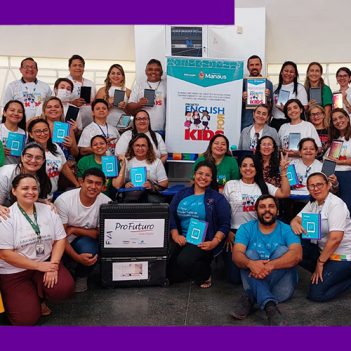 Imagem mostra grupo de educadores de Manaus reunidos em uma sala de aula. Entre eles, é possível ver a maleta do Aula Digital e um banner com o nome do projeto English for Kids