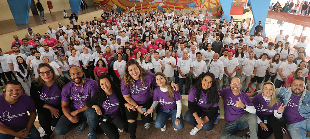 Imagem mostra um grupo de mais de 100 pessoas reunidas que atuaram como voluntárias no dia dos voluntários