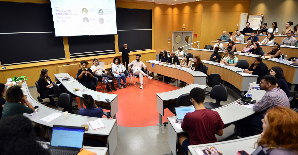 Imagem mostra a sala de conferência onde ocorreu o lançamento da pesquisa, com os convidados e palestrantes sentados ao centro da roda de debates e o público nas cadeiras ao redor