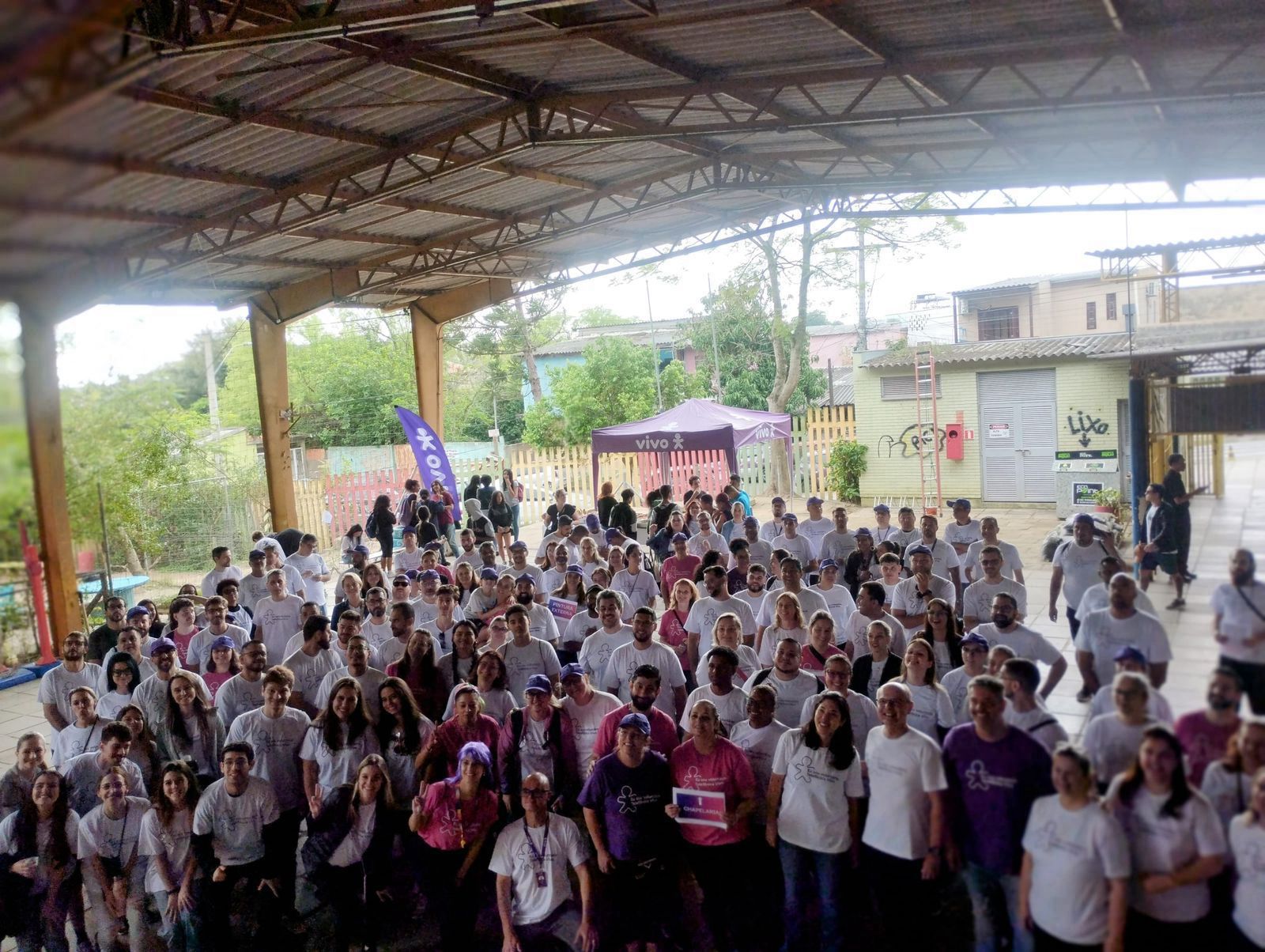 Dia dos Voluntários RS: imagem panorâmica reúne um grande grupo de voluntários, que posa para a foto diante de um palco no pátio da escola.