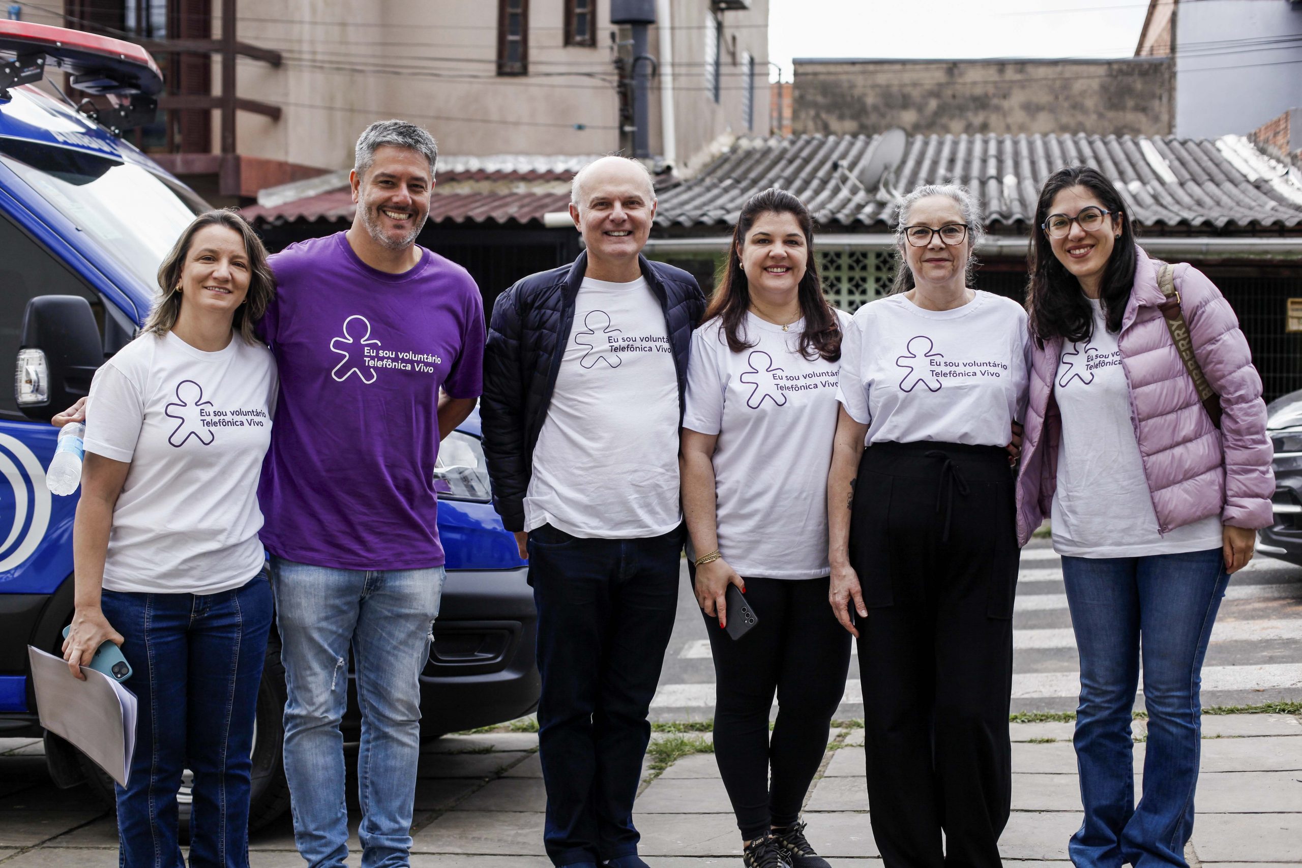 Voluntários posam para foto em frente à rua.