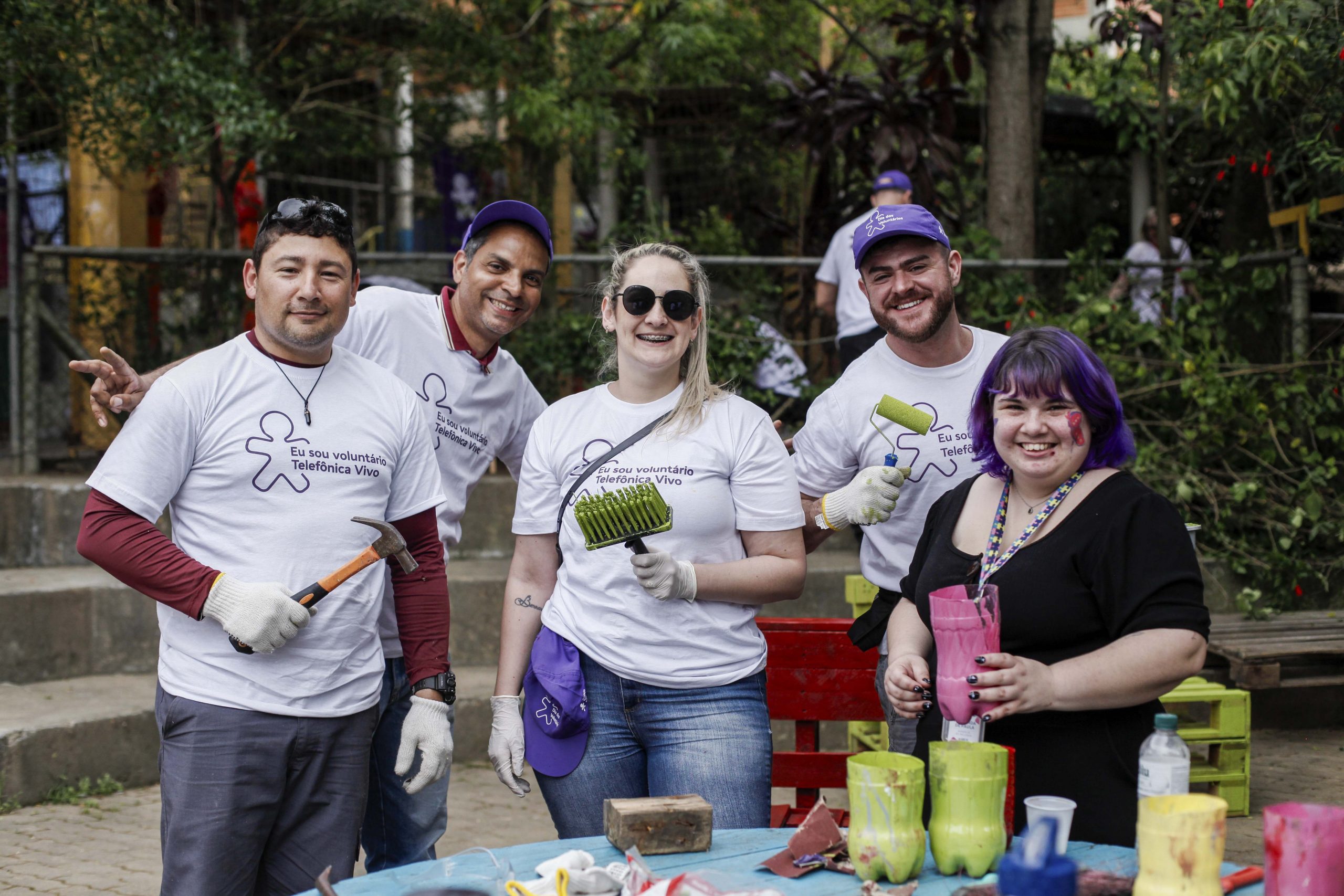 Cinco voluntários posam para foto com materiais de pintura e manutenção.