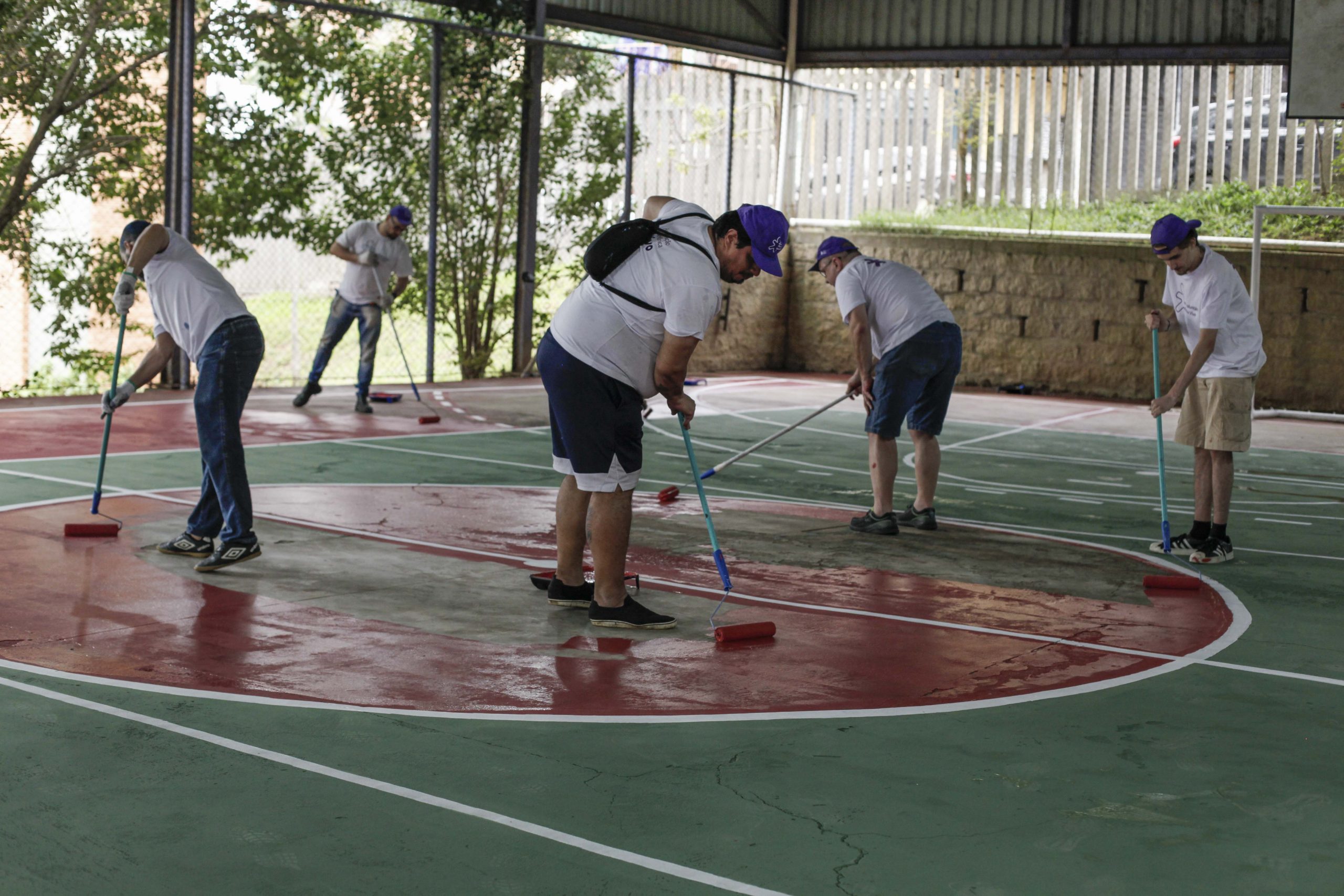 Voluntários esfregam o chão da quadra.