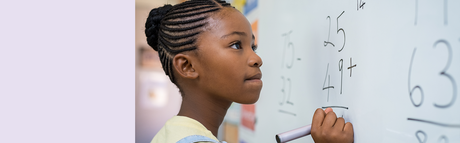 A imagem mostra uma aluna negra jovem em frente a uma lousa, onde há uma conta simples de matemática.