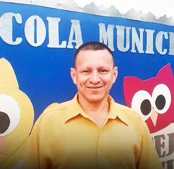 Homem de camisa amarela em frente a muro azul.