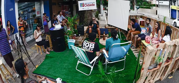 Pessoas estão sentadas em parklet montado pelo Laboratório da Cidade, um dos projetos que remodelam a relação entre cidades e pessoas.