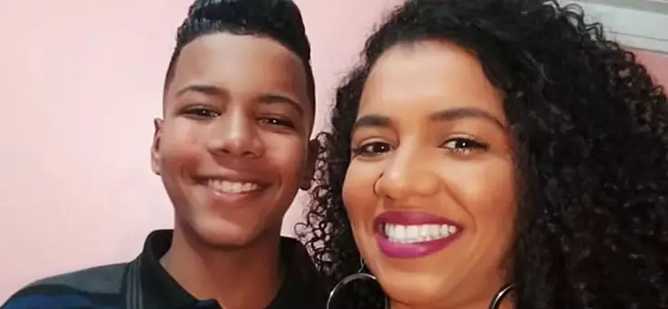 Amanda Amparo, usando batom e com cabelos na altura do ombro e encaracolados, posa ao lado do filho Willian, hoje com 13 anos. A especialista em política para juventude precisou lidar com gravidez na adolescência.