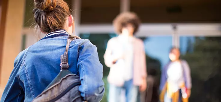 Jovem usando coque e jaqueta jeans, com mochila no ombro, ilustra matéria sobre gravidez na adolescência.