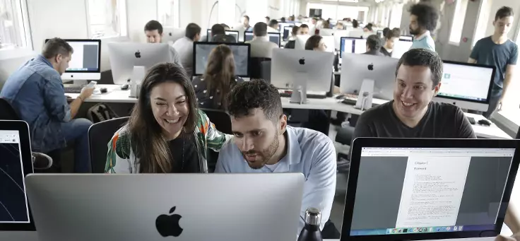 Imagem mostra um laboratório com diversos MAcbooks e pessoas